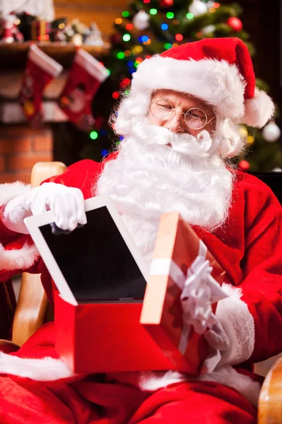Weihnachtsmann steckt digitales Tablet in Geschenkbox — Stockfoto
