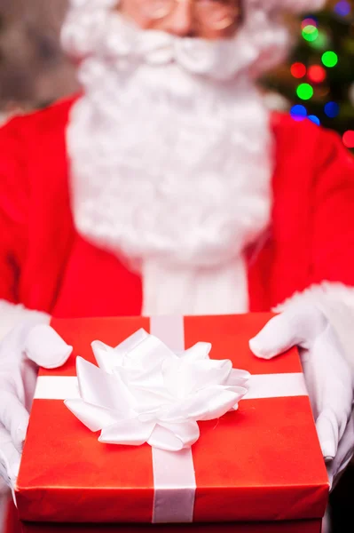 Santa Claus sträcker ut en presentförpackning — Stockfoto