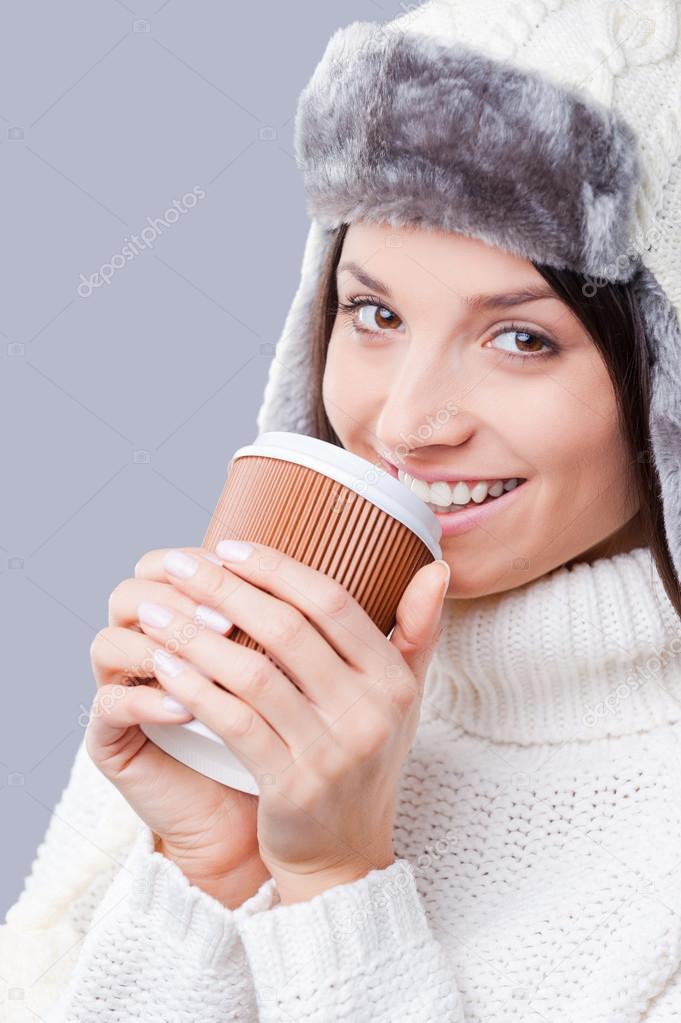 Woman in warm winter clothing drinking coffee