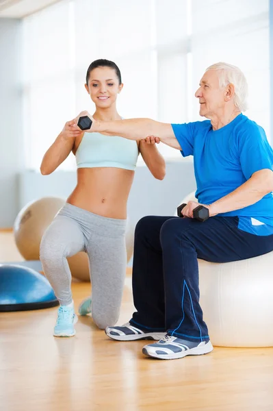 Personal trainer helping senior man — Stock Photo, Image