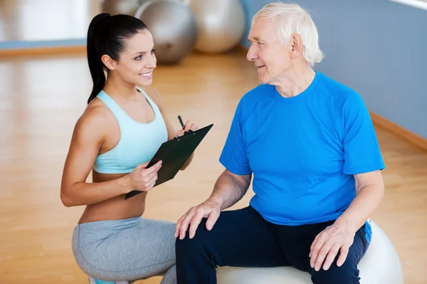 Physical therapist sitting close to senior man — Stock Photo, Image