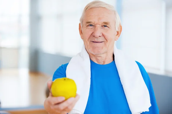 Mann streckt grünen Apfel in Fitnessstudio aus — Stockfoto