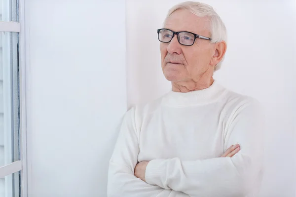 Homme âgé réfléchi gardant les bras croisés — Photo