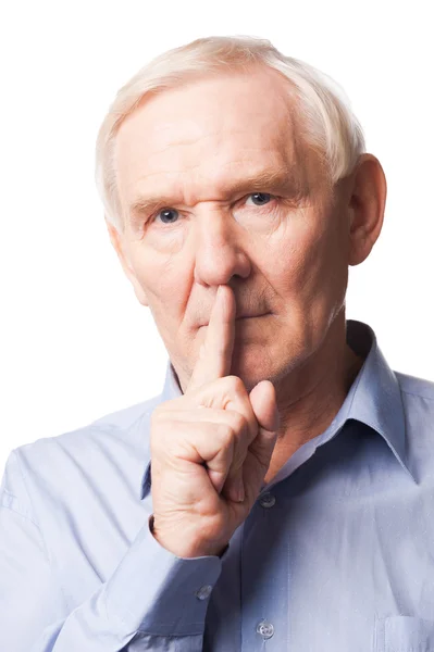 Hombre mayor sosteniendo el dedo en los labios — Foto de Stock
