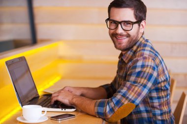 Dizüstü bilgisayarda çalışan genç adam.