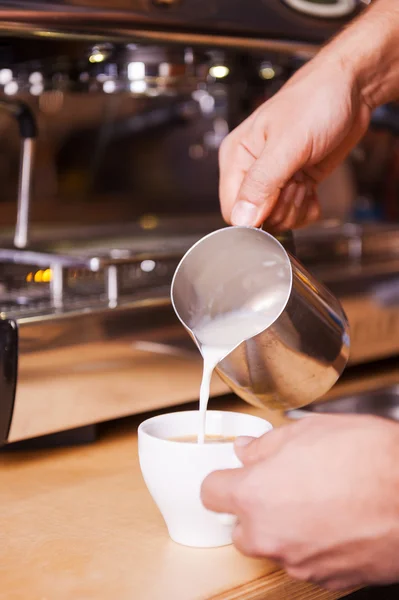 Бариста наливает молоко в чашку кофе — стоковое фото