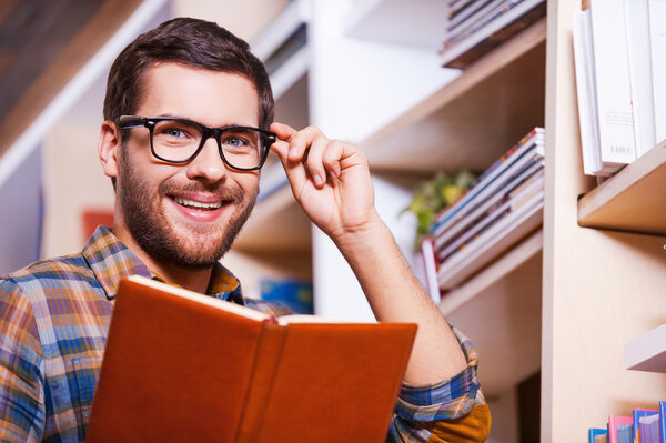 Young man holding book and smiling