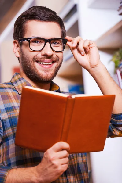 Junger Mann hält Buch und lächelt — Stockfoto