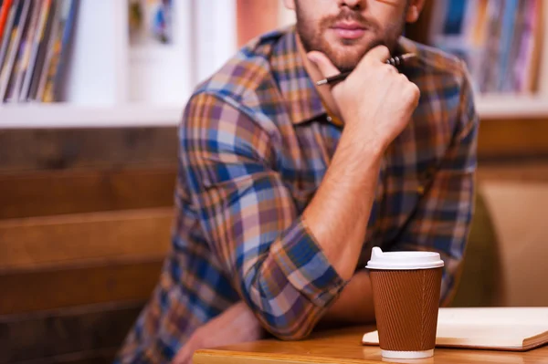 Nachdenklicher Mann sitzt am Schreibtisch in Bibliothek — Stockfoto