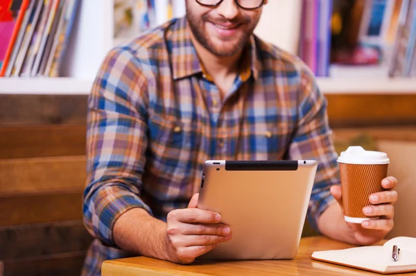 Kahve fincanı tutarak ve dijital tablet vasıl arayan genç adam — Stok fotoğraf