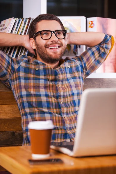 Man sitting at the desk with bookshelf — Stock Photo, Image