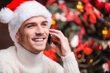 Adam cep telefonu üzerinde konuşurken Noel Baba şapkası