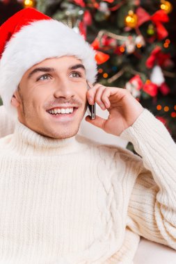 Adam cep telefonu üzerinde konuşurken Noel Baba şapkası