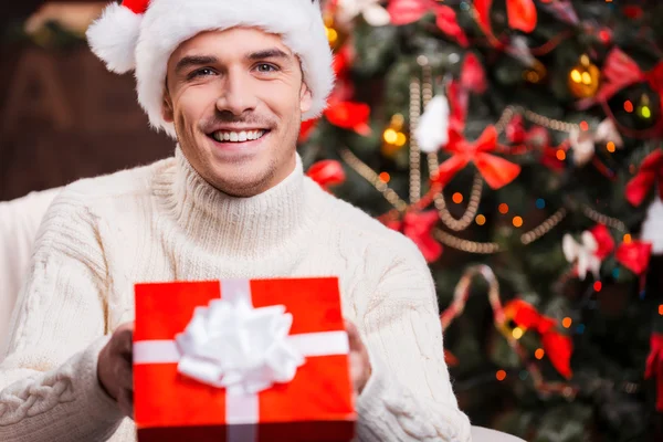 Uomo in cappello Babbo Natale allungando scatola regalo — Foto Stock