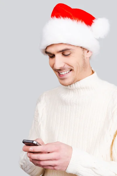 Człowiek w Santa hat trzymając telefon komórkowy — Zdjęcie stockowe