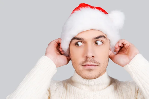 Homem olhando para longe e ajustando chapéu de Papai Noel — Fotografia de Stock