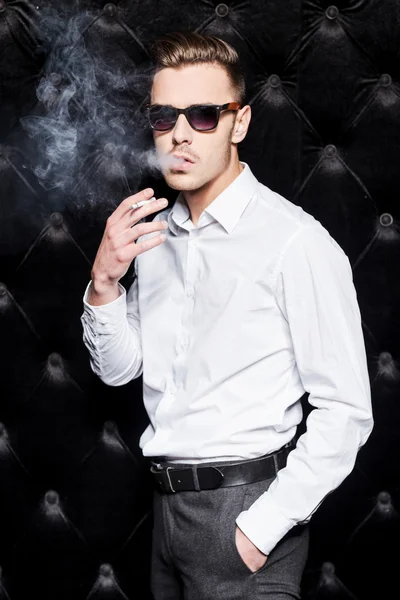 Hombre joven con camisa blanca fumando cigarrillo — Foto de Stock