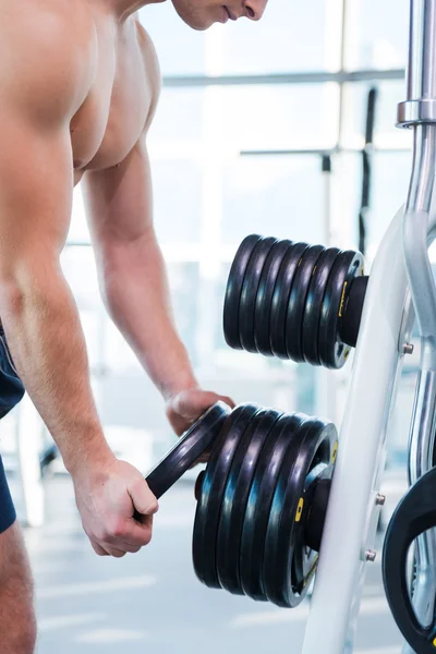 Hombre muscular que elige el peso para hacer ejercicio —  Fotos de Stock