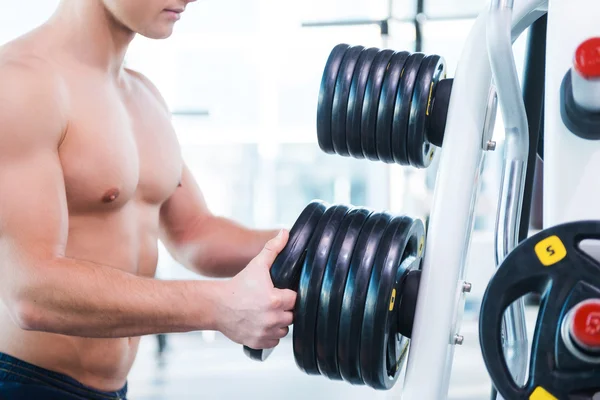Muskularny mężczyzna wybierając wagi do ćwiczeń — Zdjęcie stockowe