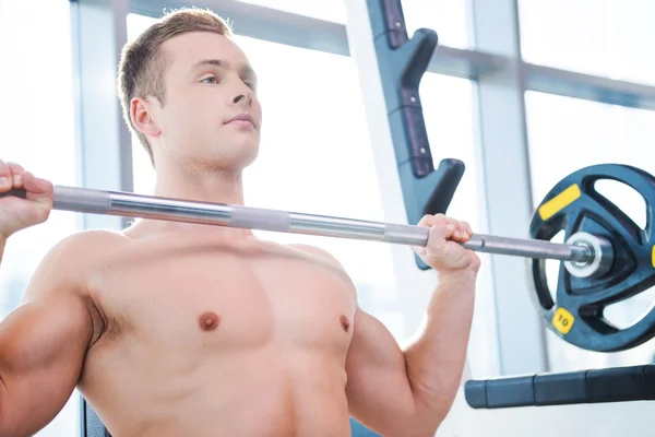 Musculoso hombre haciendo ejercicio en press de banca — Foto de Stock