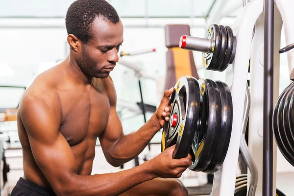 Hombre africano que elige el peso para hacer ejercicio —  Fotos de Stock