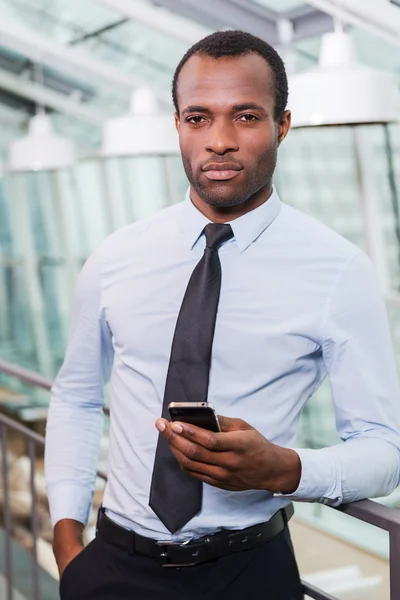 Africký muž v košili a kravatu, drží mobilní telefon — Stock fotografie