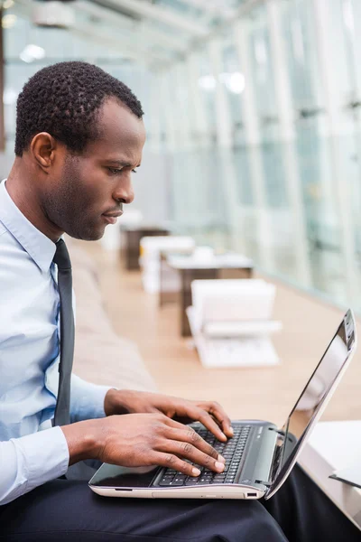 Hombre africano en ropa formal trabajando en el ordenador portátil — Foto de Stock