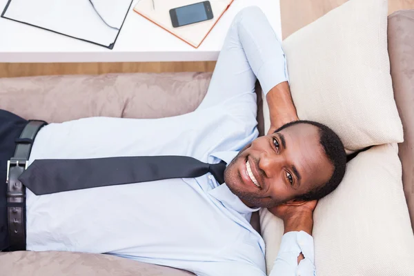 Afrykański mężczyzna leżąc na kanapie — Zdjęcie stockowe