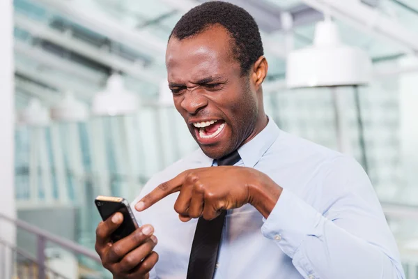 Gefrustreerd Afrikaanse man met mobiele telefoon — Stockfoto