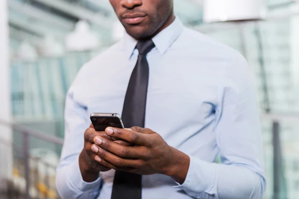 Afrikansk man i skjorta och slips textning på telefon — Stockfoto