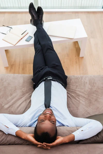 Afrikansk man i formalwear liggande på soffan — Stockfoto