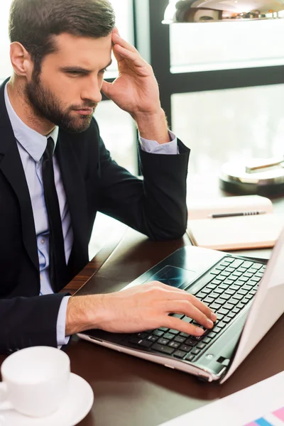 Junger Mann im Anzug schaut auf Laptop — Stockfoto