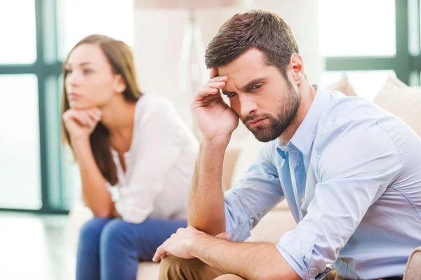 Depressed man and woman sitting behind him — Stock Photo, Image