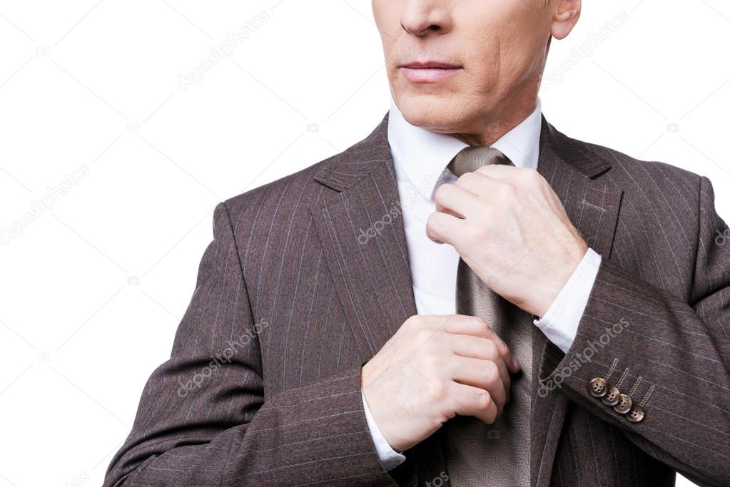 Confident mature man adjusting his necktie