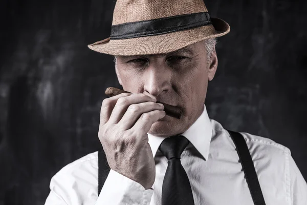 Man in hat and suspenders smelling cigar — Stock Photo, Image