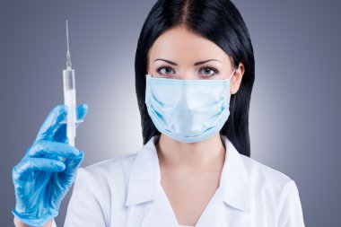 Kadın doktor elinde şırınga tutuyor.