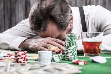 Depresif üst düzey adam kafa poker masasına yaslanmış
