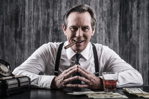 Senior man sitting at the table and smoking cigar — Stock Photo, Image