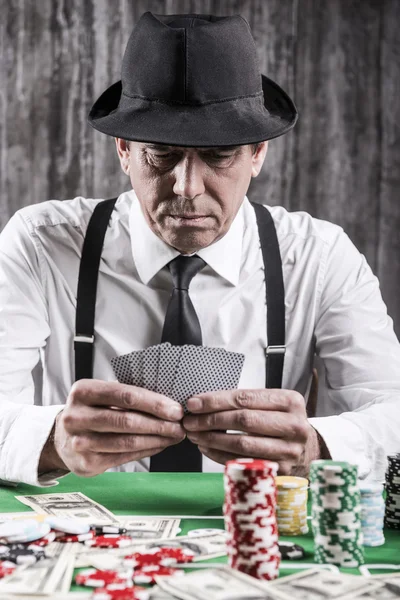 Homem sênior sério sentado na mesa de poker — Fotografia de Stock