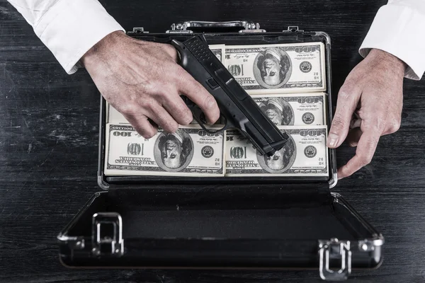 Man holding gun and briefcase full of currency — Stock Photo, Image