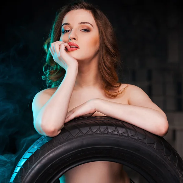 Женщина без рубашки, прислонившаяся к автомобильной шине — стоковое фото