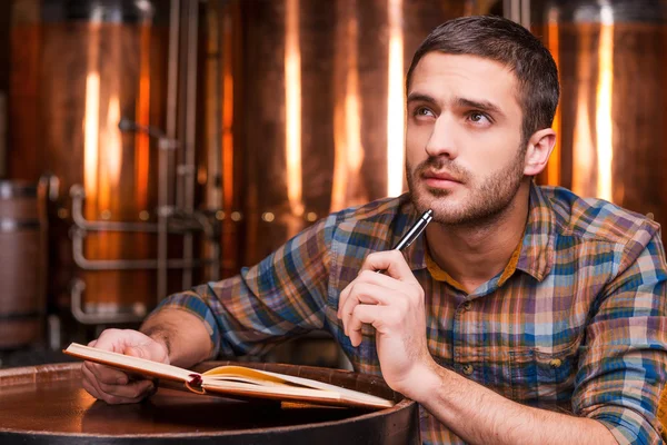 Thoughtful young man holding note pad — Stock Photo, Image