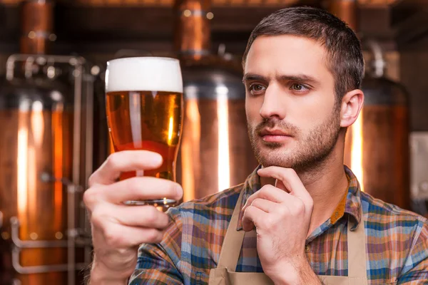 Brasseur dans tablier tenant verre avec bière — Photo