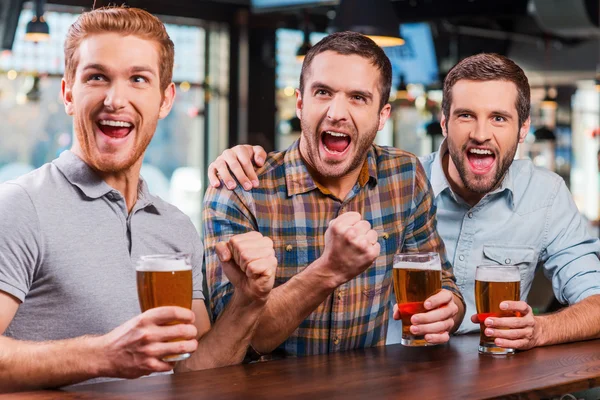 Hombres sosteniendo cerveza y viendo el partido de fútbol en el bar — Foto de Stock