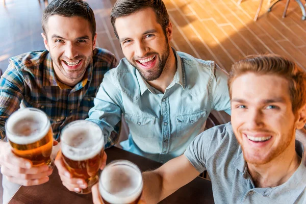 Junge Männer stoßen in Bar mit Bier an — Stockfoto