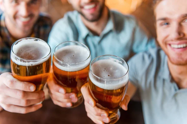 Junge Männer stoßen in Bar mit Bier an — Stockfoto