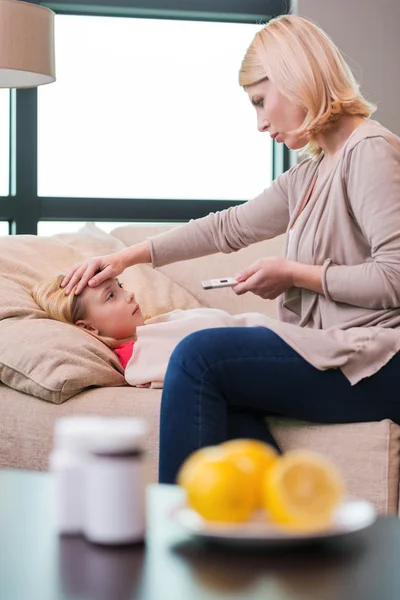 Moeder touching voorhoofd van zieke dochter — Stockfoto