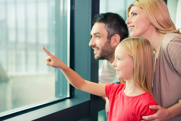 Lyckliga familjen tittar genom fönstret — Stockfoto