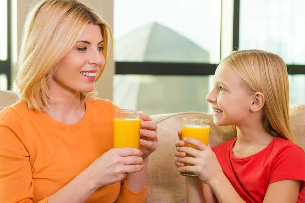 Mother and daughter holding glasses with orange juice — Stock Photo, Image