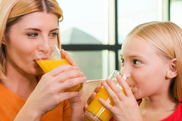 Mãe e filha bebendo suco de laranja — Fotografia de Stock